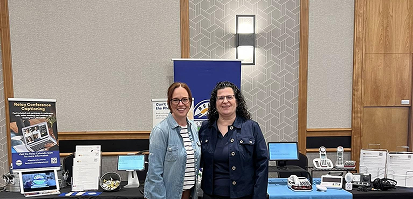 Staff members at a resource booth displaying assistive technology and early hearing detection materials that support Colorado families with Deaf, Hard of Hearing, and DeafBlind children